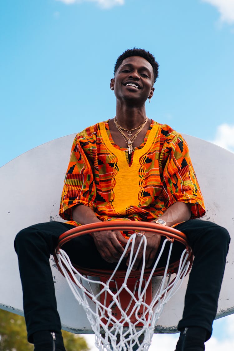 Man Sitting On Basketball Ring