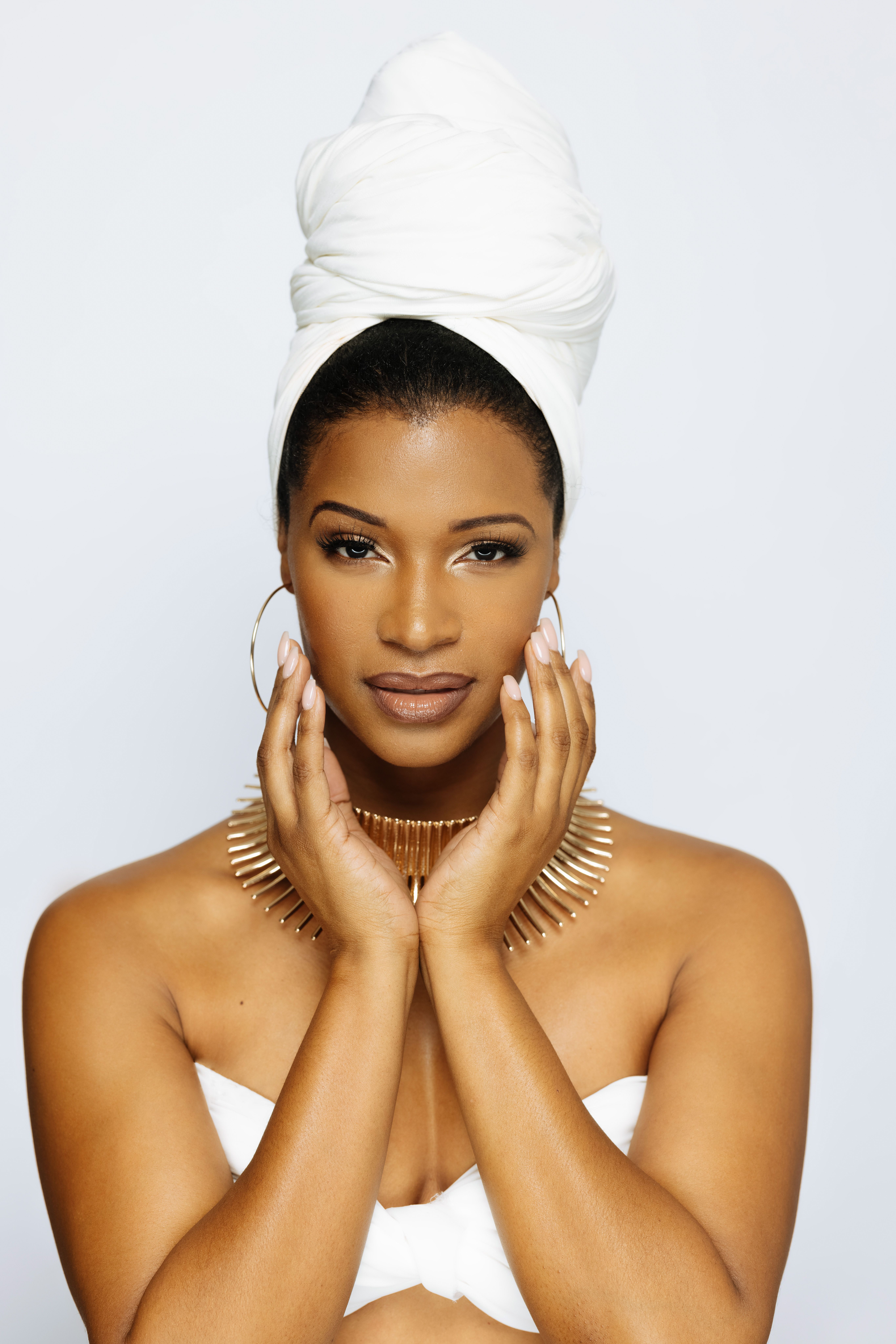 Stylish photo of a woman in a studio, wearing a turban and striking jewelry, exuding elegance and confidence.