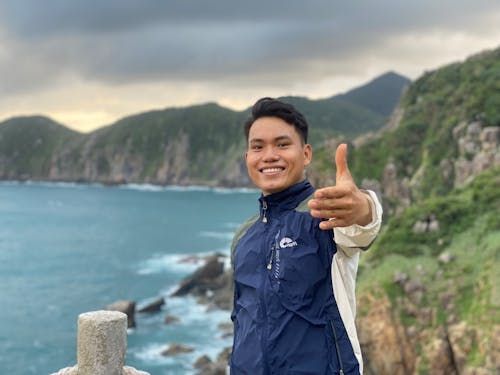 A man giving the thumbs up while standing on a cliff