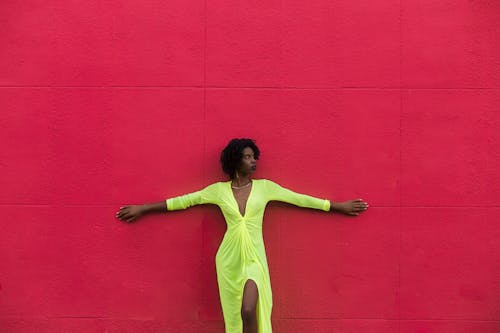 Woman Wearing a Green Summer Dress and Standing against a Red Wall