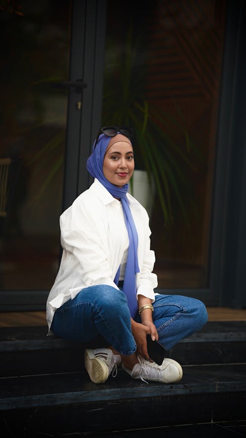 Woman Wearing Blue Jeans and a Blue Headscarf Sitting Cross Legged
