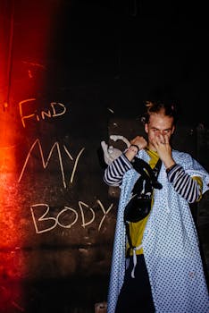 在昏暗的光线下，一位表演者对着满是涂鸦的墙壁，呈现出一幅怪异的肖像