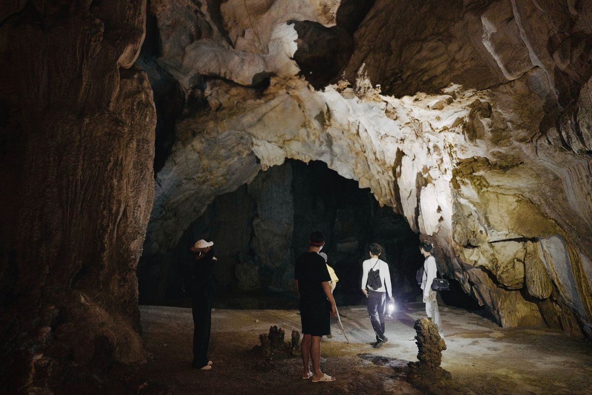 Grupo de aventureros explorando una enorme cueva con formaciones geológicas