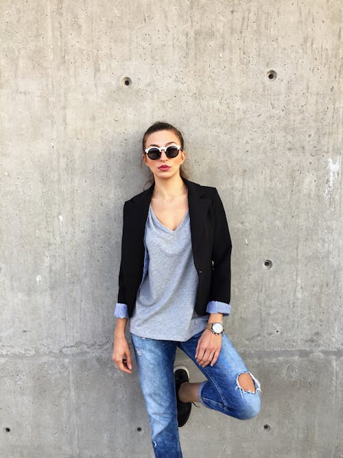 Free Woman Wearing Sunglasses Leaning on Concrete Wall With Left Toe on Wall Stock Photo