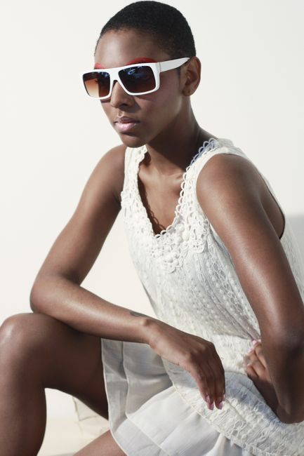 Elegant fashion portrait of a stylish woman in sunglasses and white dress.