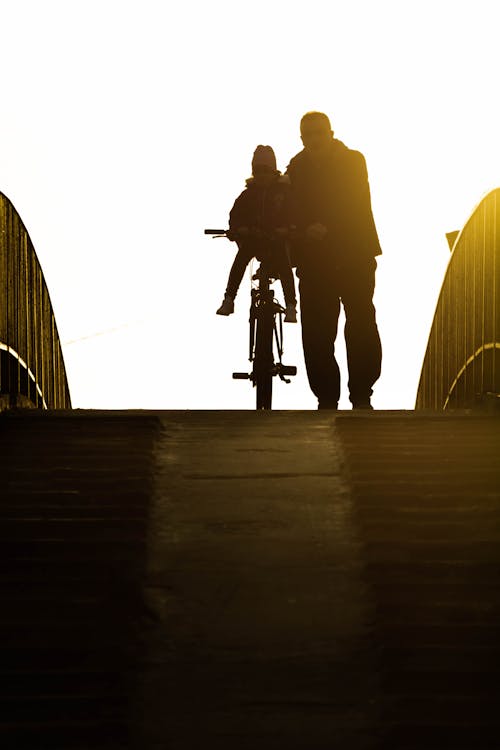 Silhouette of a Man with his Child on a Bicycle 