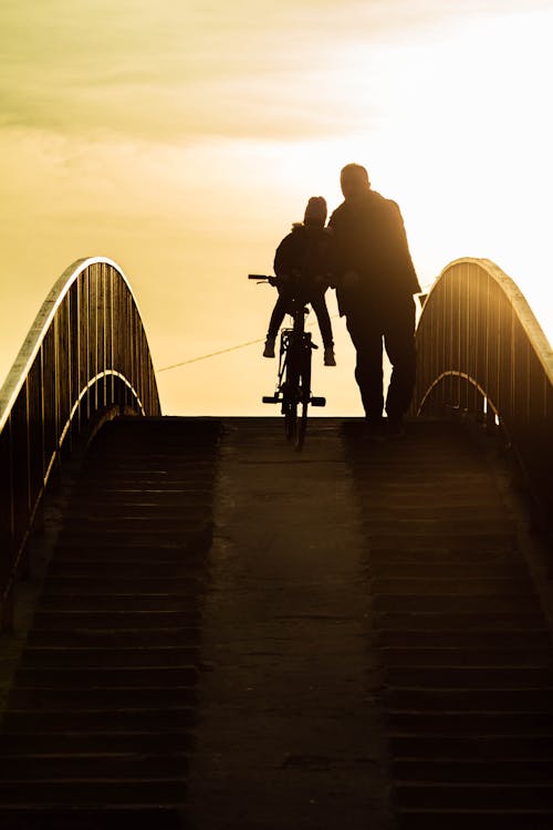 Two People with a Bicycle on a Bridge