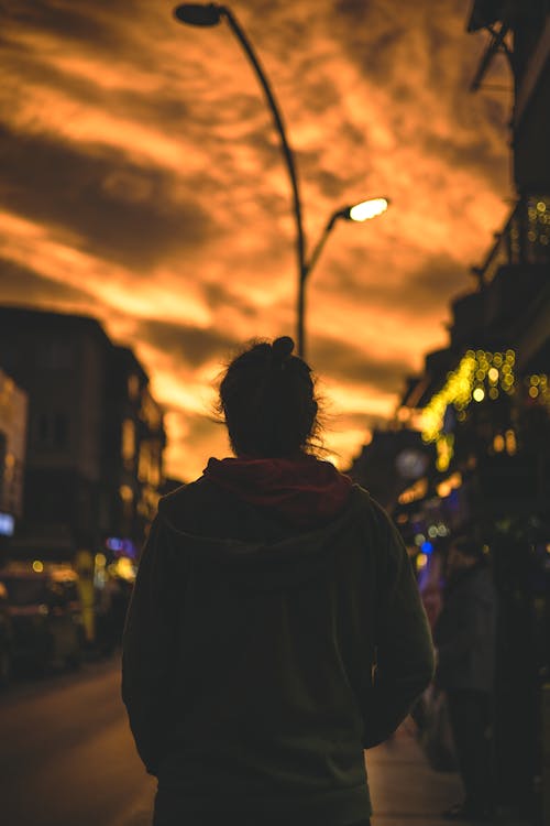 Man in Hoodie in Town at Sunset