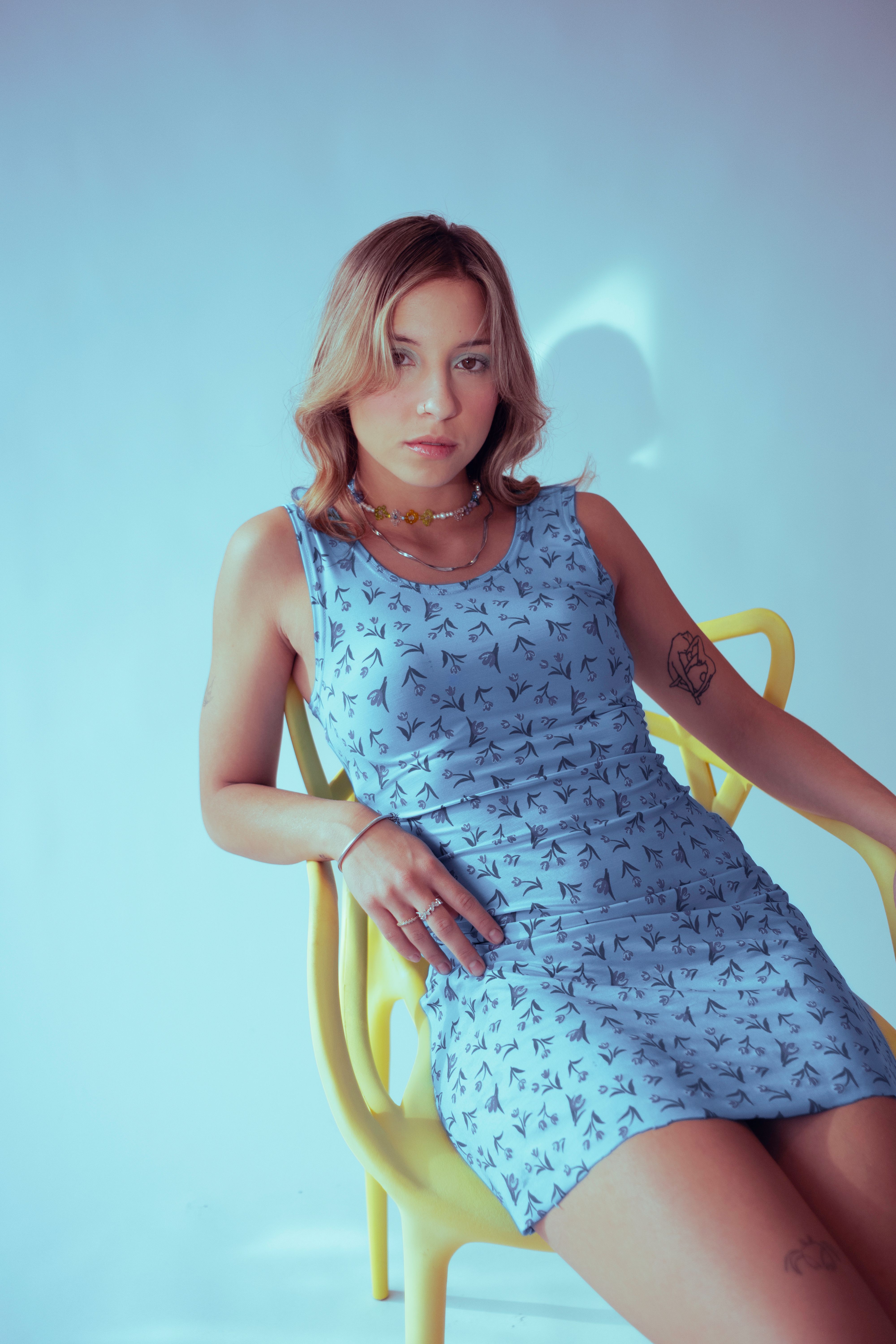 A woman in a blue dress sitting on a yellow chair · Free Stock Photo