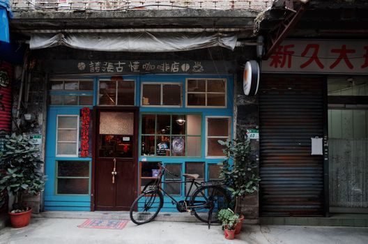 Explore a charming vintage coffee shop with a bicycle parked outside, framed by vibrant blue doors.