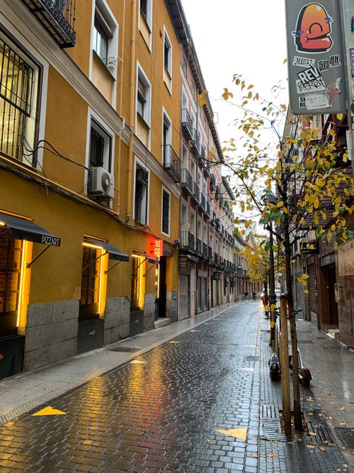 Free A picturesque narrow cobblestone street in Madrid after rain, with classic architecture and warm lighting. Stock Photo