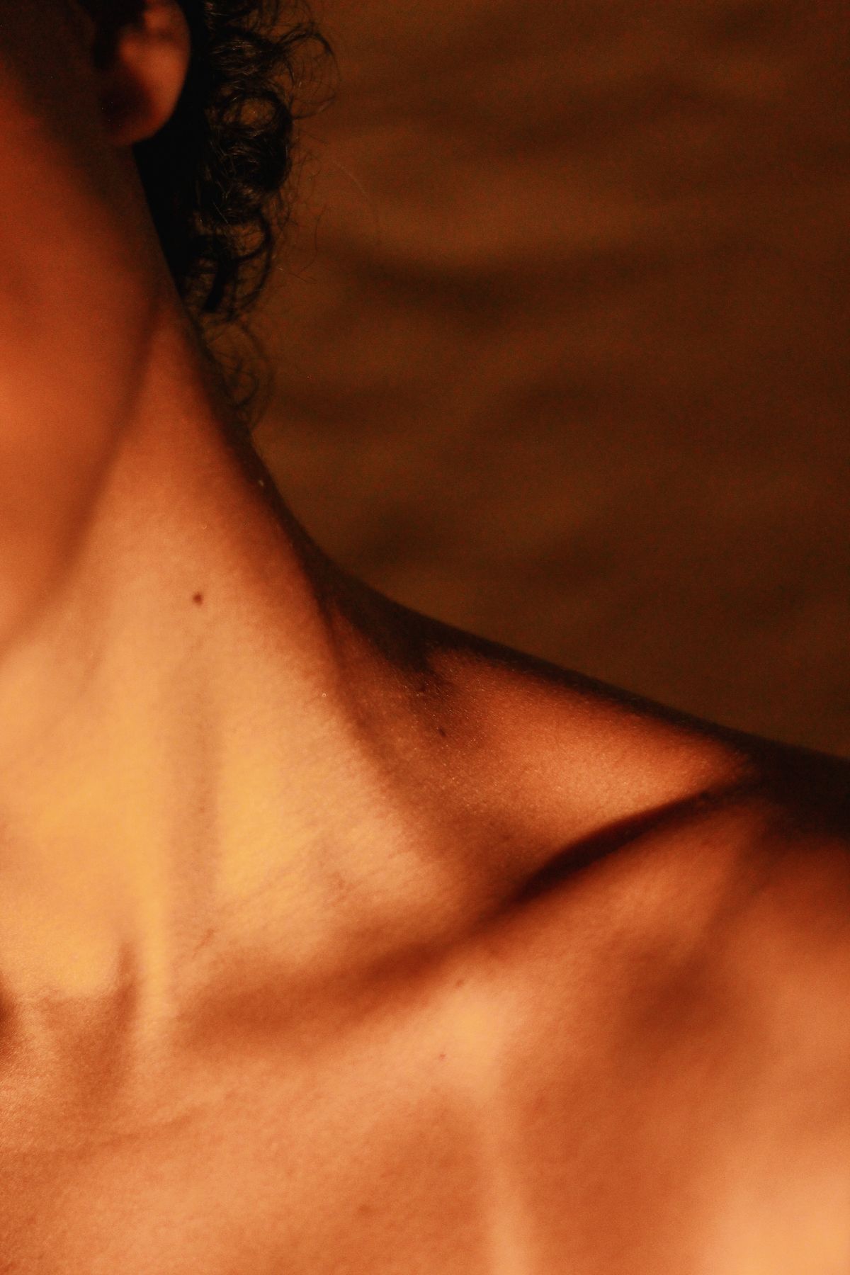 Close-up of a woman's evenly tanned skin in warm golden light, illustrating a self tanning routine that looks natural