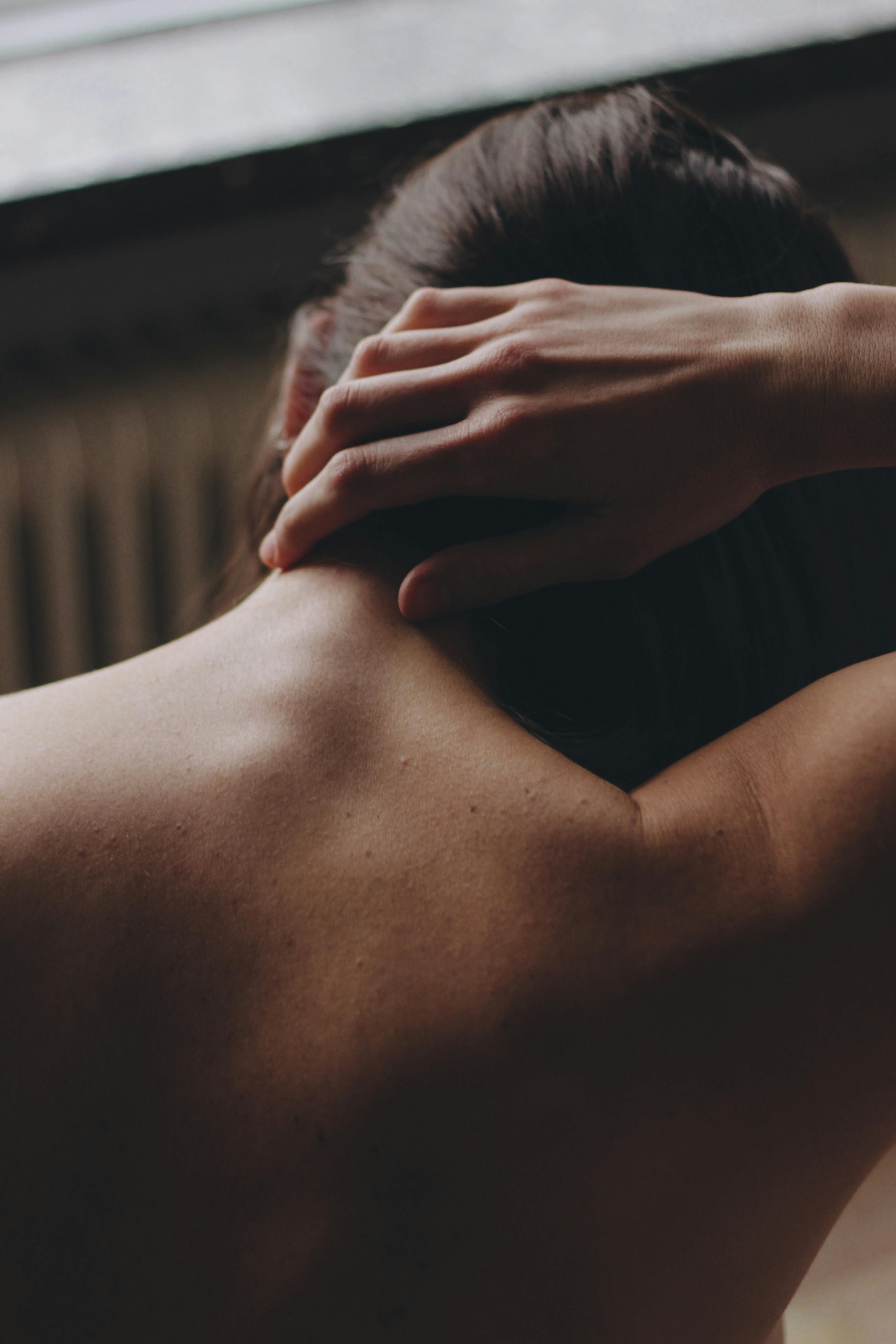 Relaxing image of a woman's back with a gentle hand on her neck, symbolizing calm and introspection.