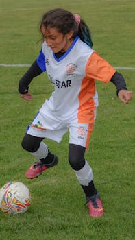 A young girl wearing sportswear plays soccer, focusing on controlling the ball during training.