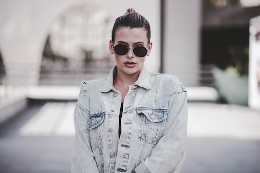 Young woman wearing sunglasses and a denim jacket in an urban setting. Fashionable and modern look.