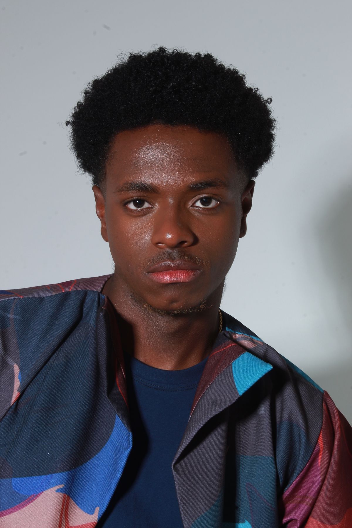 Man with short tightly curled hair in a studio portrait