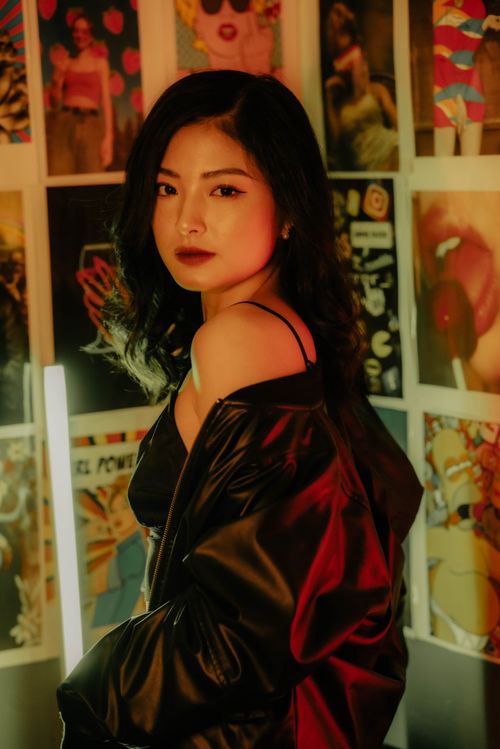 Free Portrait of a fashionable young woman in a leather jacket posing against an artistic backdrop. Stock Photo