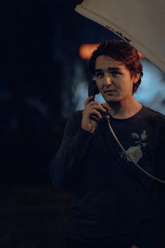Portrait of a young man using a payphone at night in Fethiye, capturing an urban atmosphere.