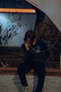 A man sitting outside using a public pay phone at night in Fethiye, Türkiye.