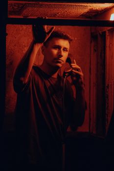 A man uses a vintage telephone in a dimly lit booth, creating a mysterious mood.
