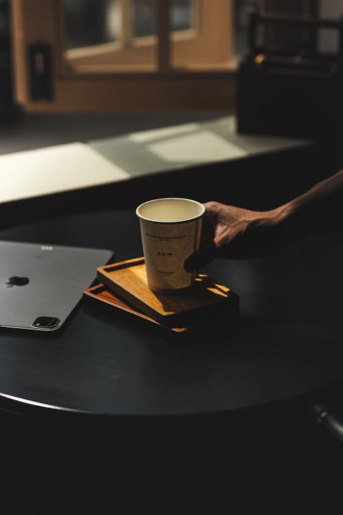 Hand with a Coffee in Disposable Cup on the Table 