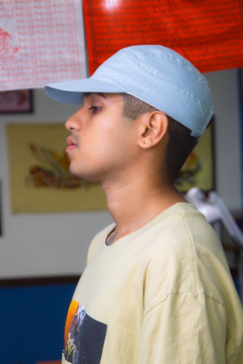 Free Side portrait of a young man in a casual outfit, wearing a baseball cap indoors. Stock Photo