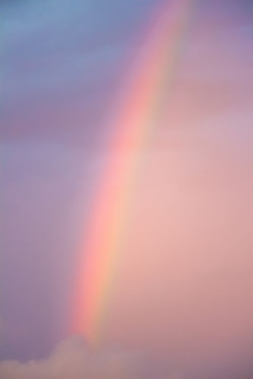 Free Beautiful rainbow arching over a colorful sky, perfect for digital backgrounds. Stock Photo