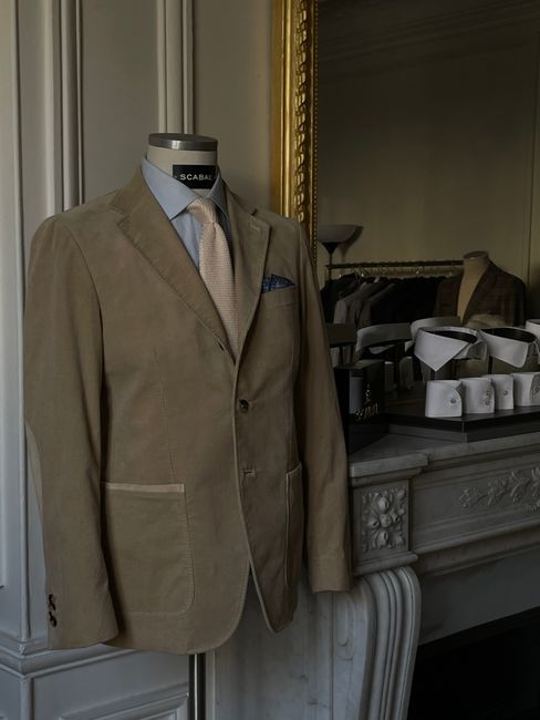 Stylish beige suit displayed on a mannequin in a tailor's shop with classic decor.