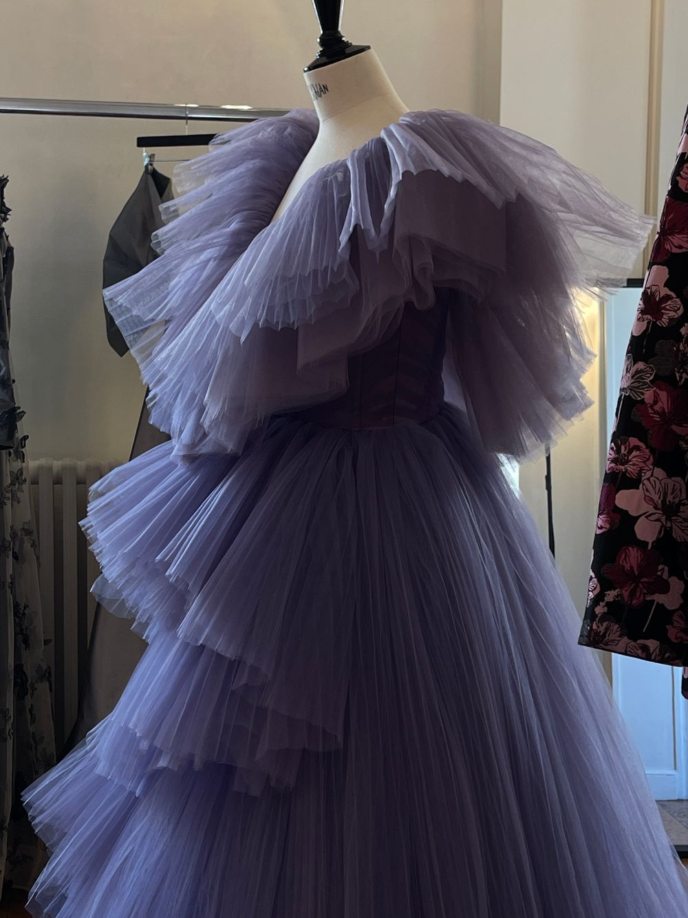 Purple evening gown displayed on a dress form in a professional fashion studio
