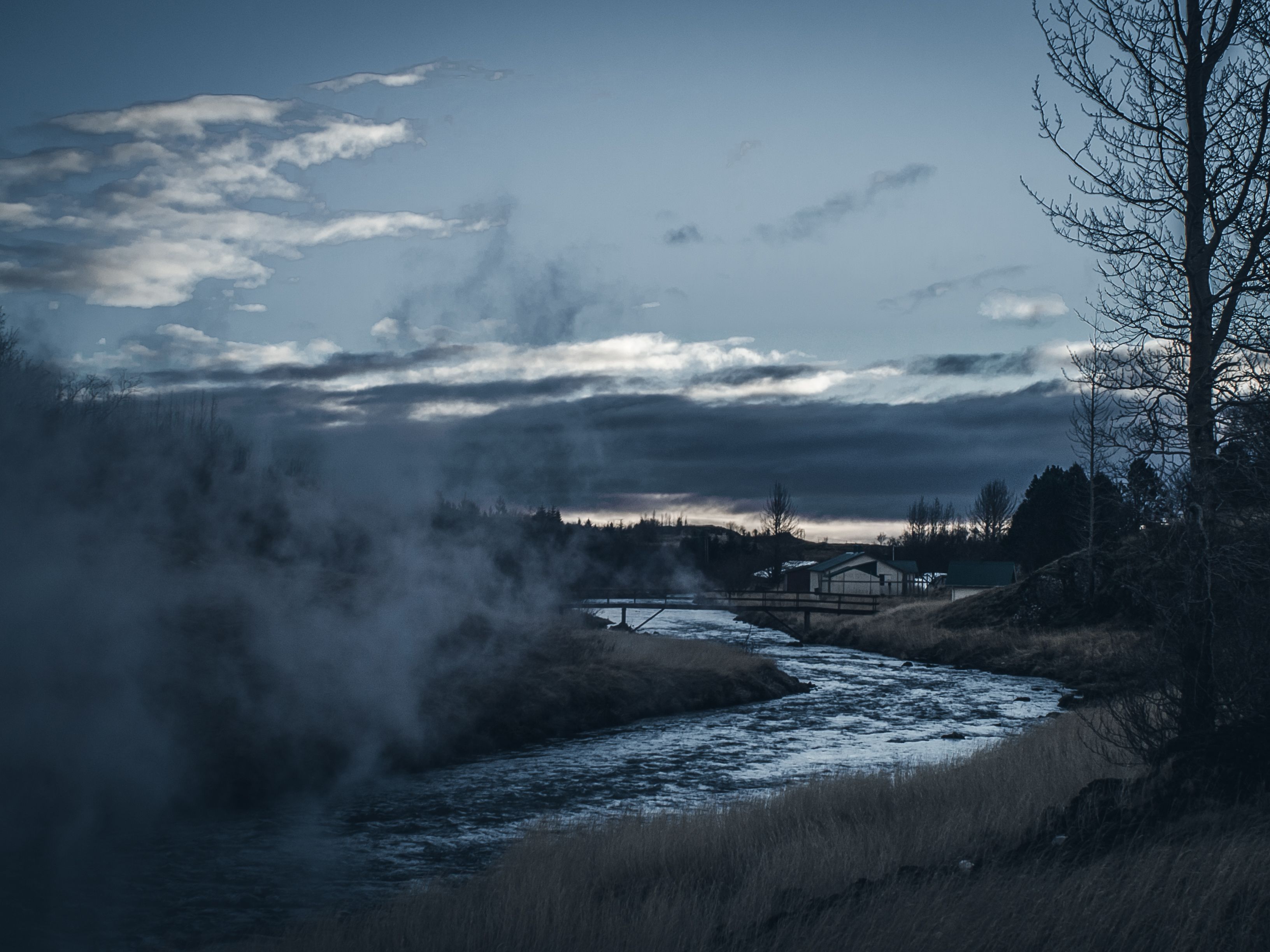 Explore the serene river and village landscape in Hveragerði, Iceland at twilight.
