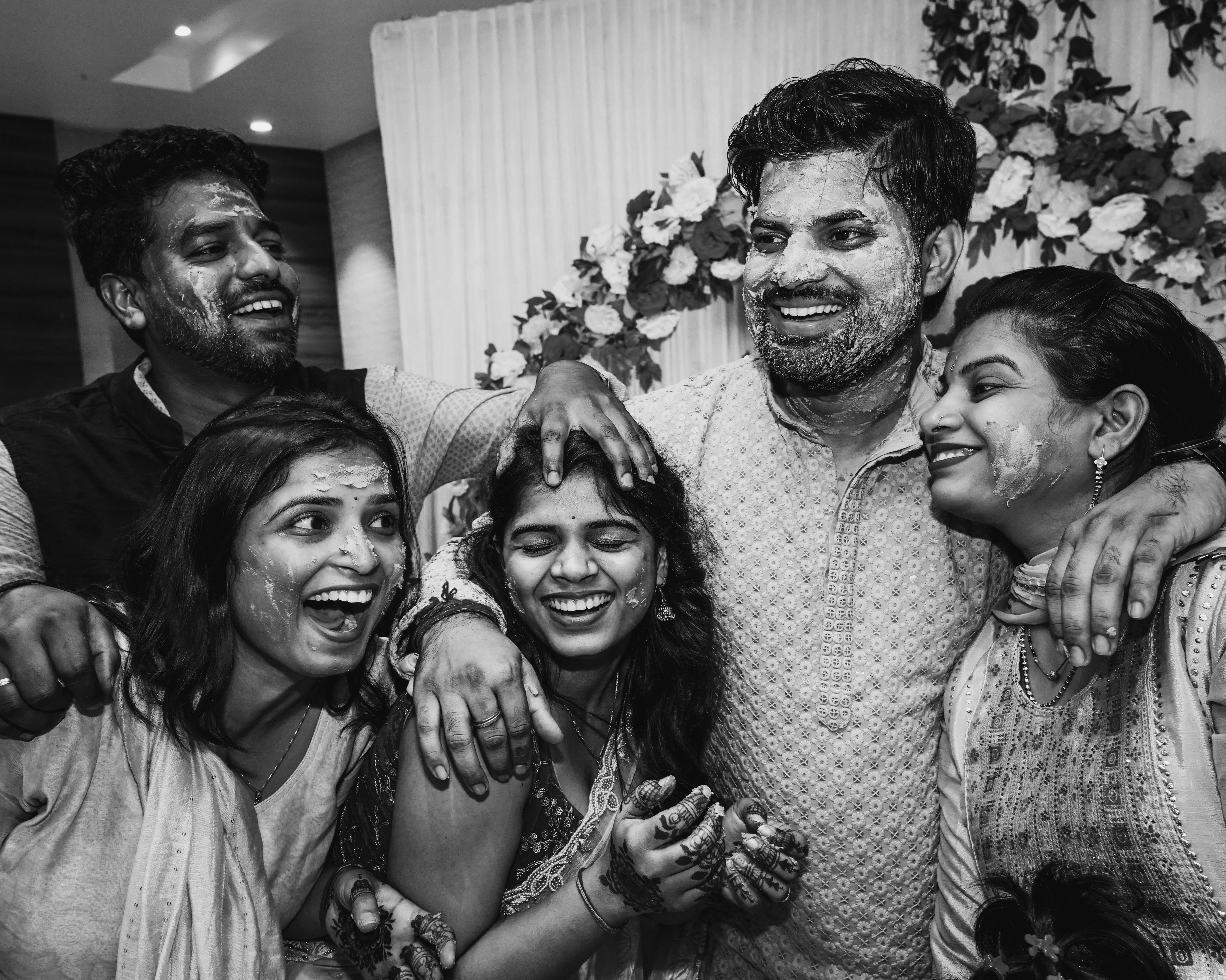A festive black and white photo of friends celebrating with laughter and paint.