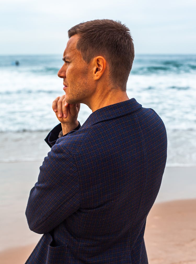 Pensive Man In A Navy Blue Checkered Blazer On The Beach