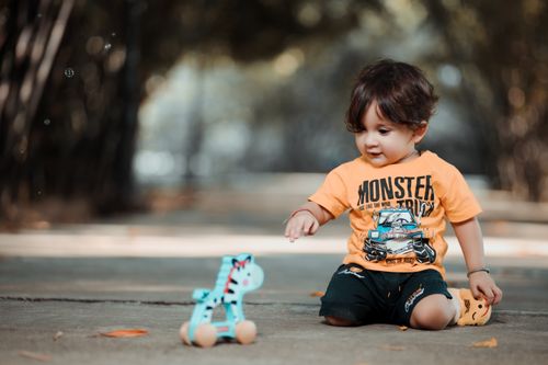 Free Adorable child in casual outfit playing with wooden toy on a sunny day. Stock Photo