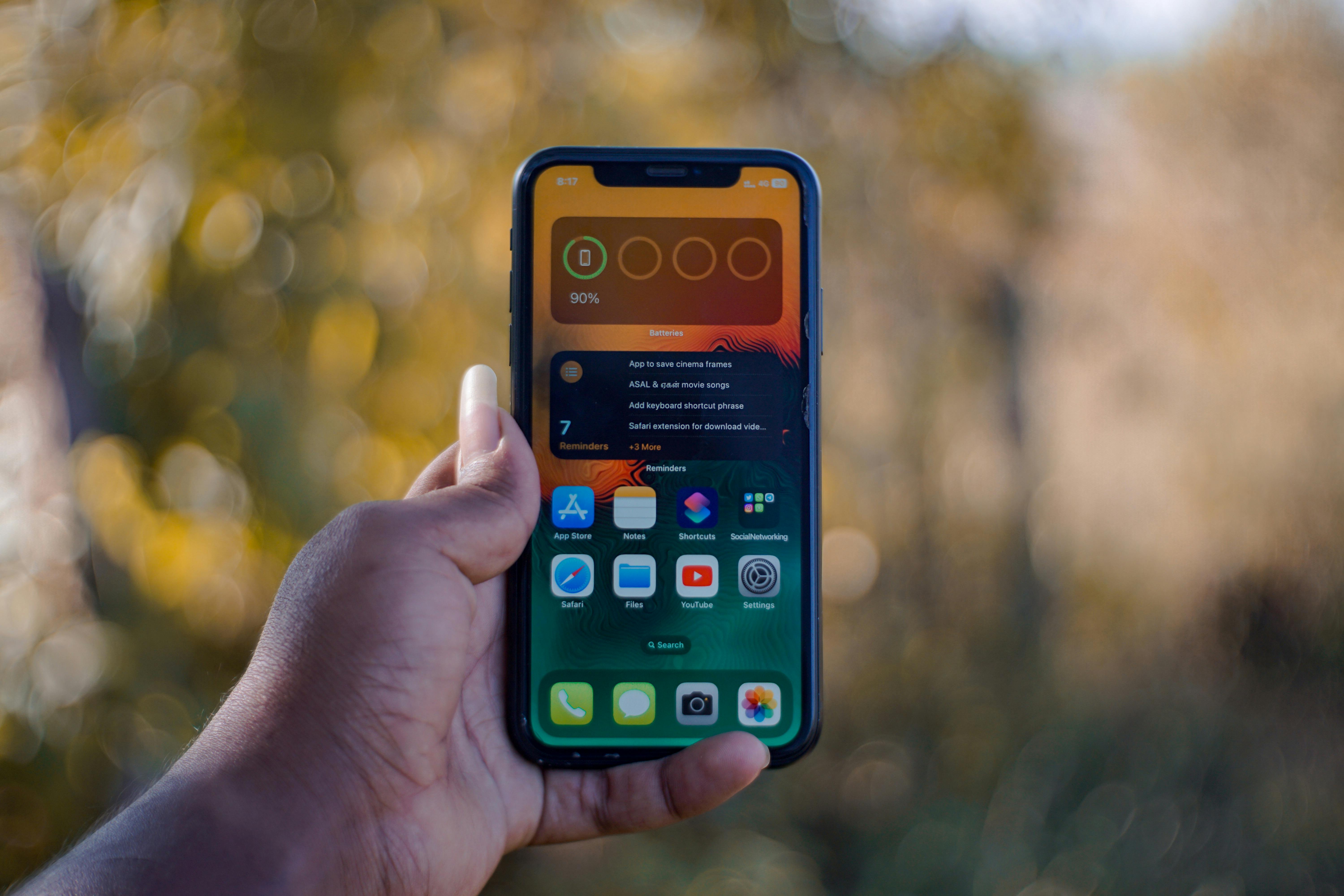Close-up of a hand holding a smartphone outdoors in TN, India, showing apps on screen.