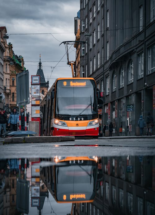 A tram is reflected in the water on a rainy day