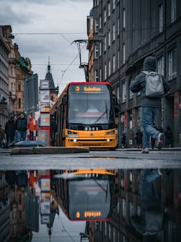 A vibrant Prague street scene showcasing a tram, reflections, and pedestrians on a rainy day.