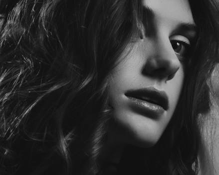 这张时尚的黑白肖像捕捉了一位眼睛深邃、卷发飘逸的女性
