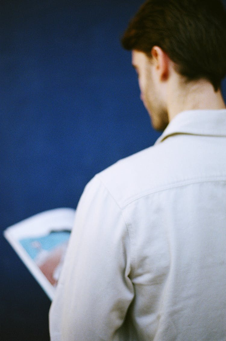 Back View Of A Young Man Holding A Magazine 