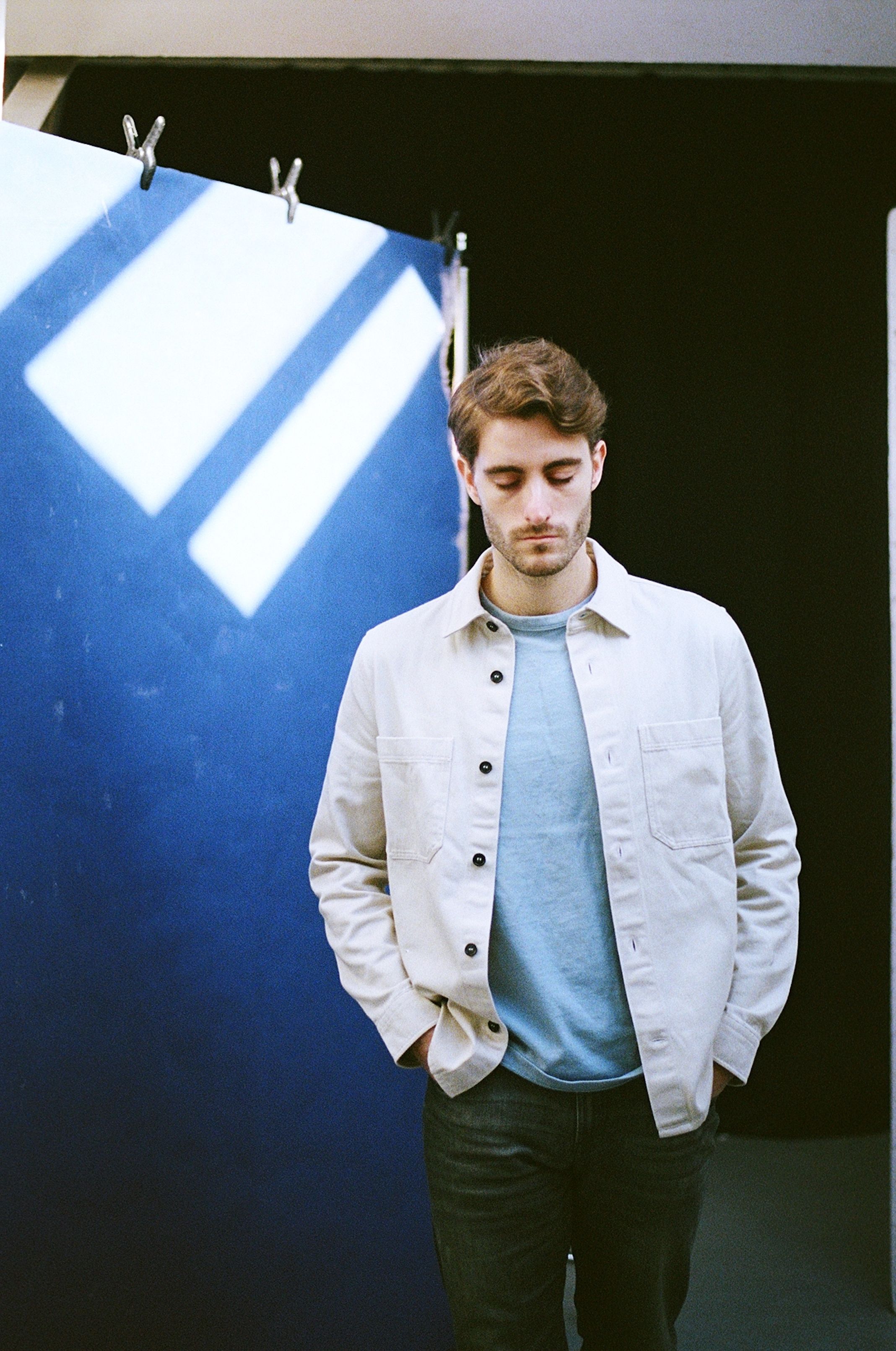 Stylish young man posing casually in a modern studio setting.