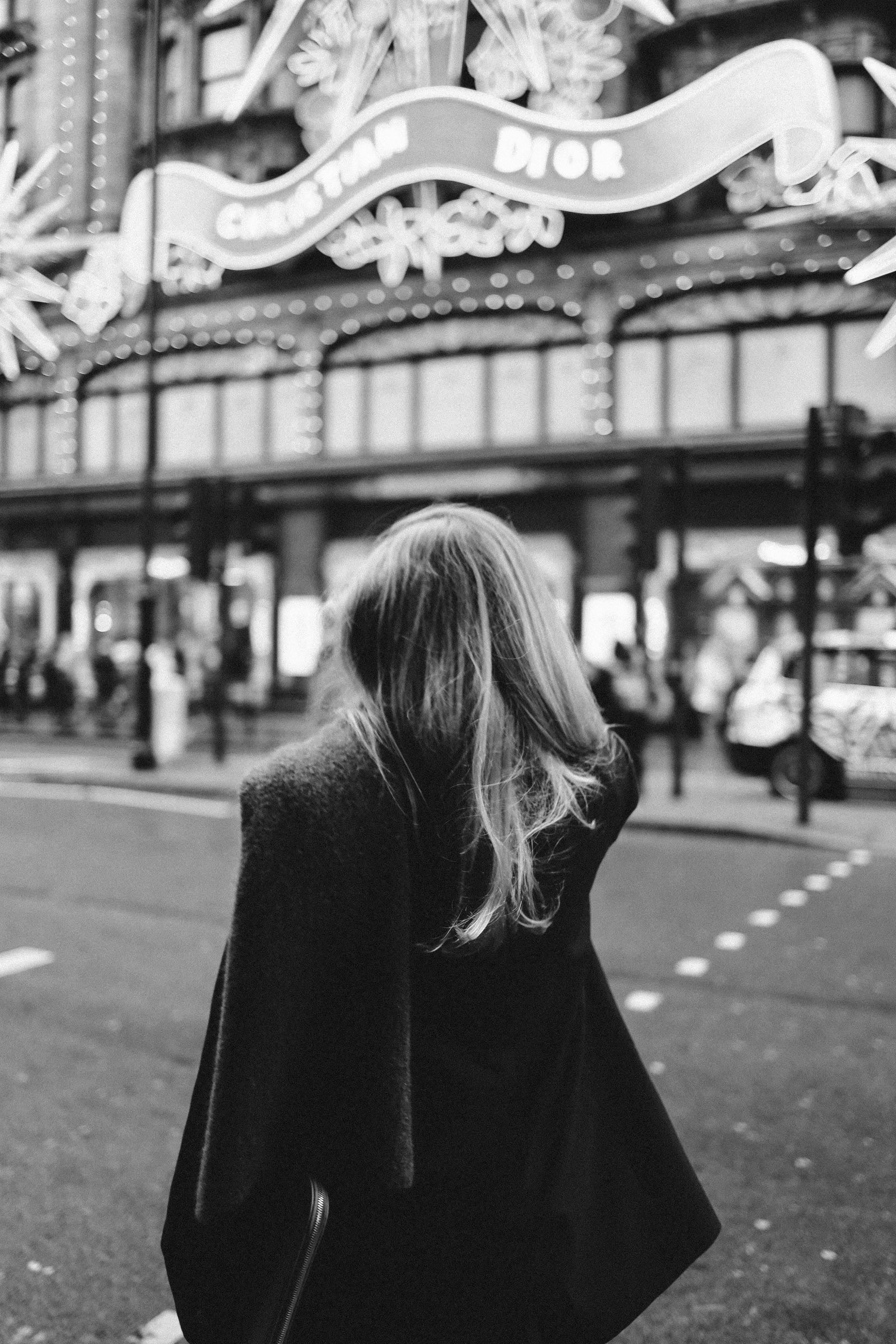 A woman stands in an urban street capturing the city's vibrant atmosphere in black and white.