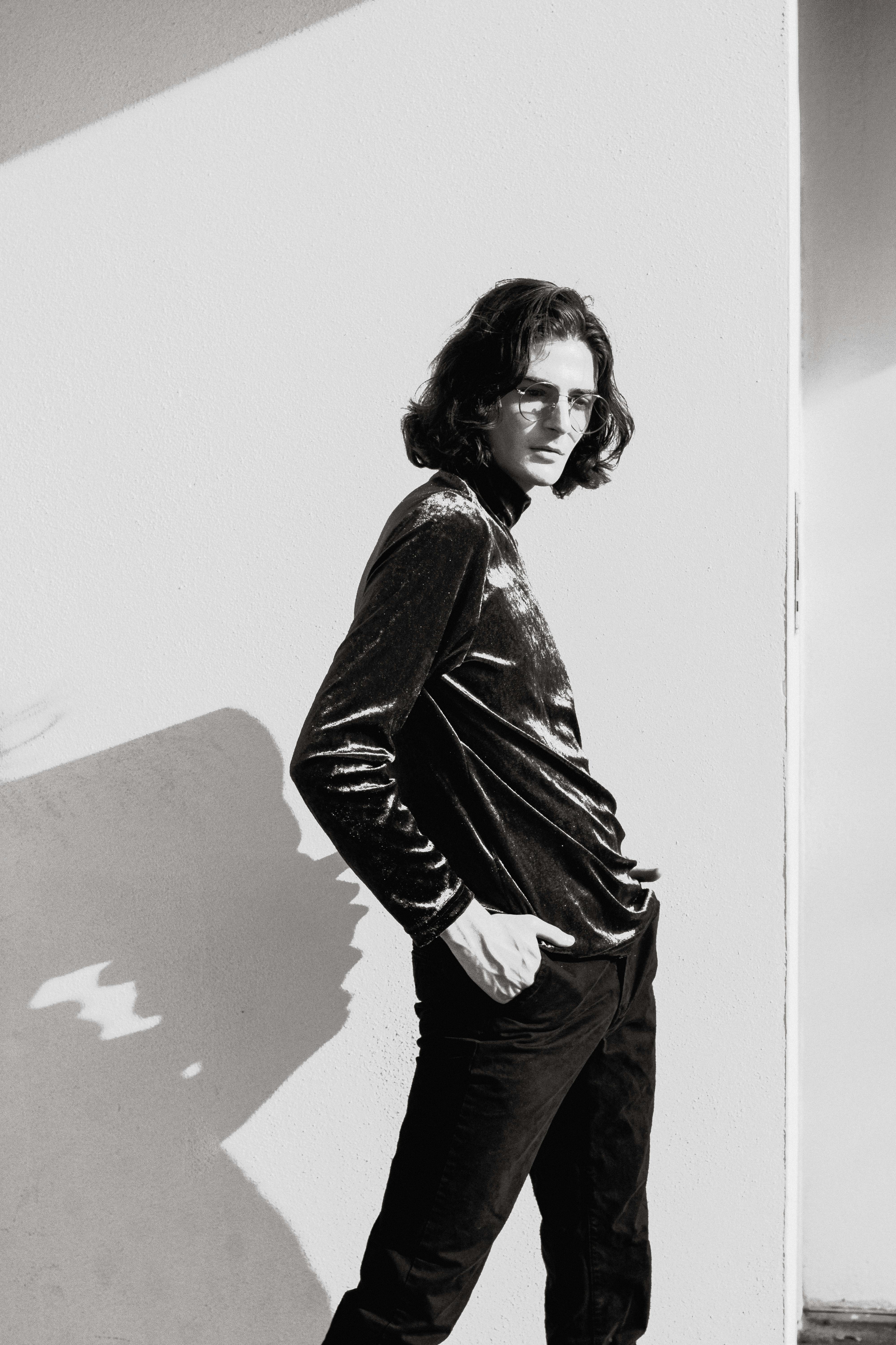 Stylish black and white portrait of a man posing with long hair and eyeglasses.