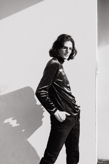 Stylish black and white portrait of a man posing with long hair and eyeglasses.
