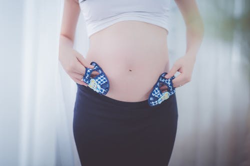 Zwangere Vrouw Met Babyschoenen In Haar Buik