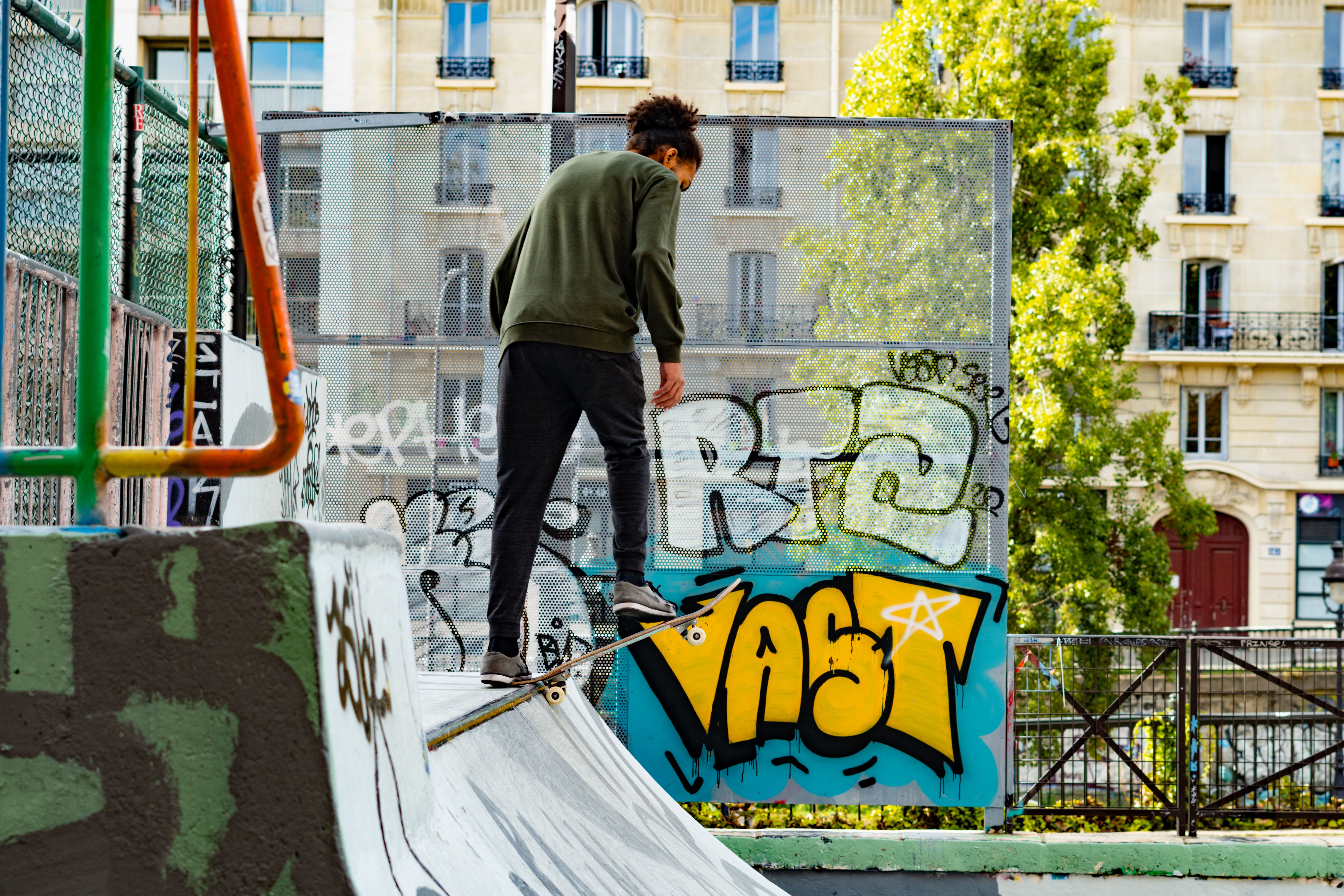 Young man skateboarding in a graffiti-covered skatepark in Paris, showcasing urban youth culture and skills.