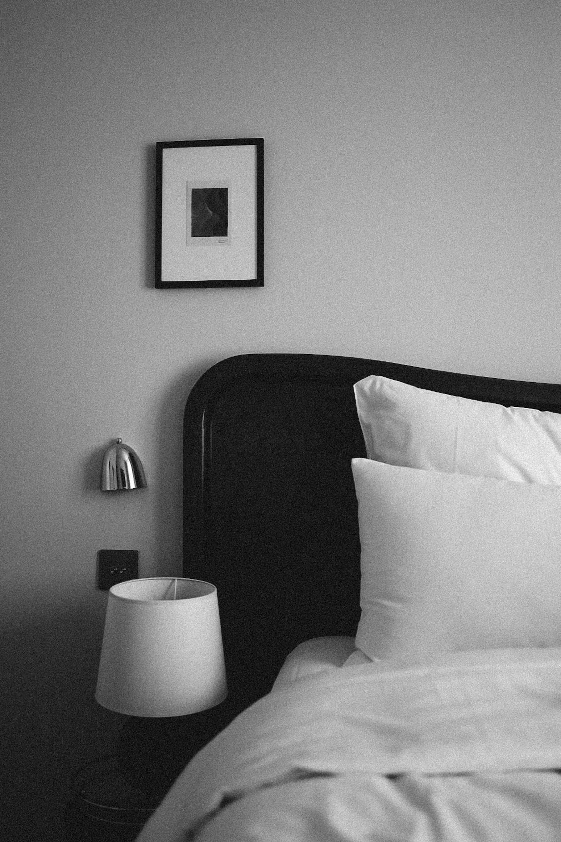 Elegant black and white bedroom with an upholstered bed, layered pillows, dark accents and warm bedside lamps