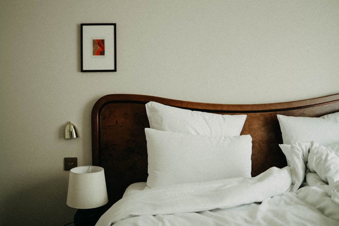 An image of a bed with white sheets and pillows 