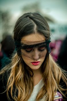 Artistic portrait of a woman with red lipstick wearing a black veil, creating a mysterious aura.