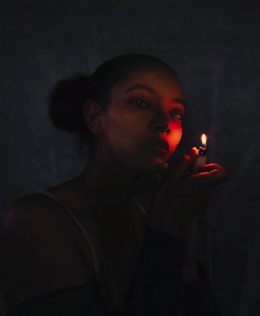 Elegant portrait of a woman with a lighter, casting intriguing shadows and light.