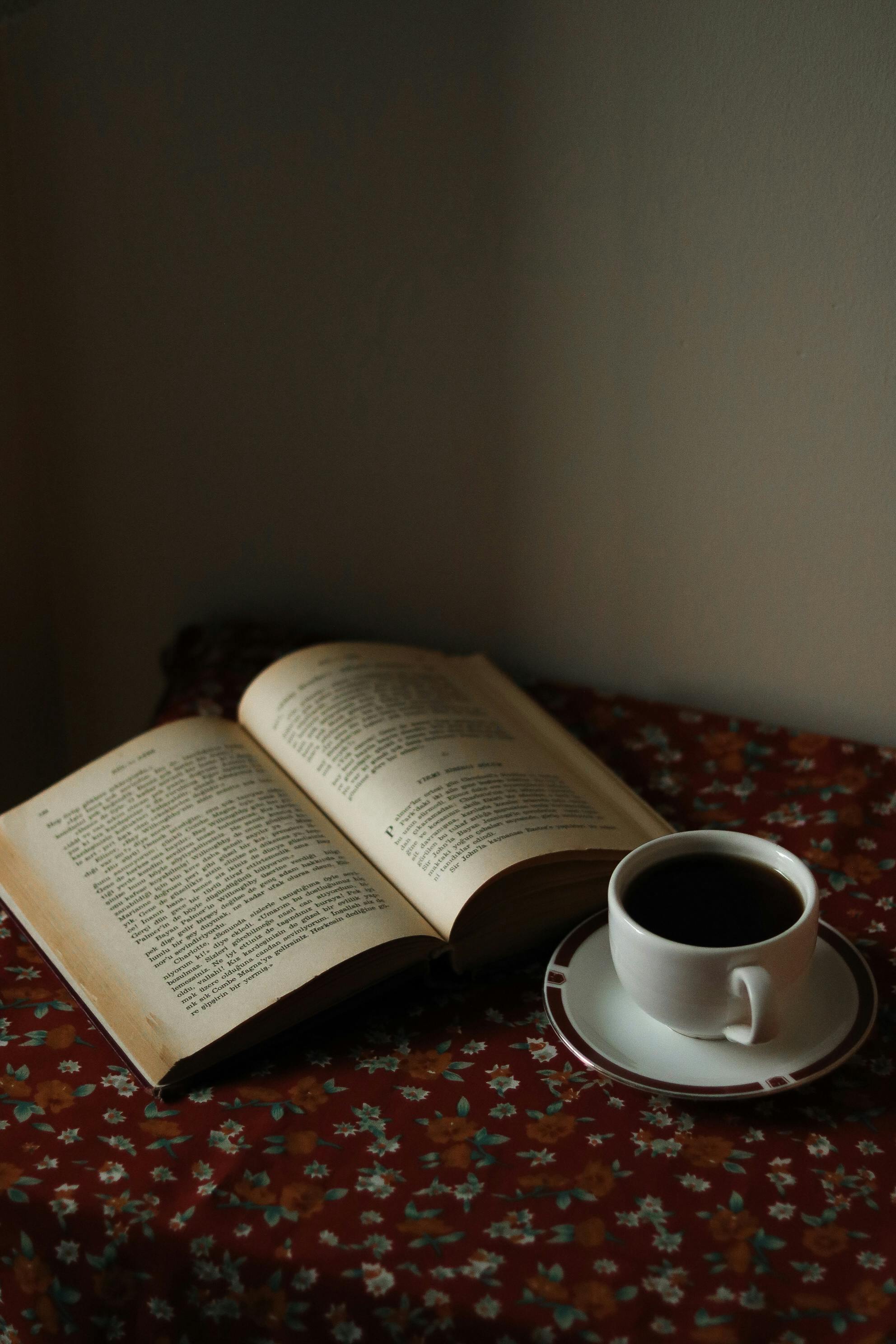 Book Opened on Top of White Table Beside Closed Red Book and Round Blue ...