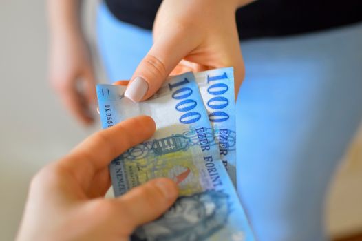 An exchange of 1000 Hungarian Forint banknotes between two hands.